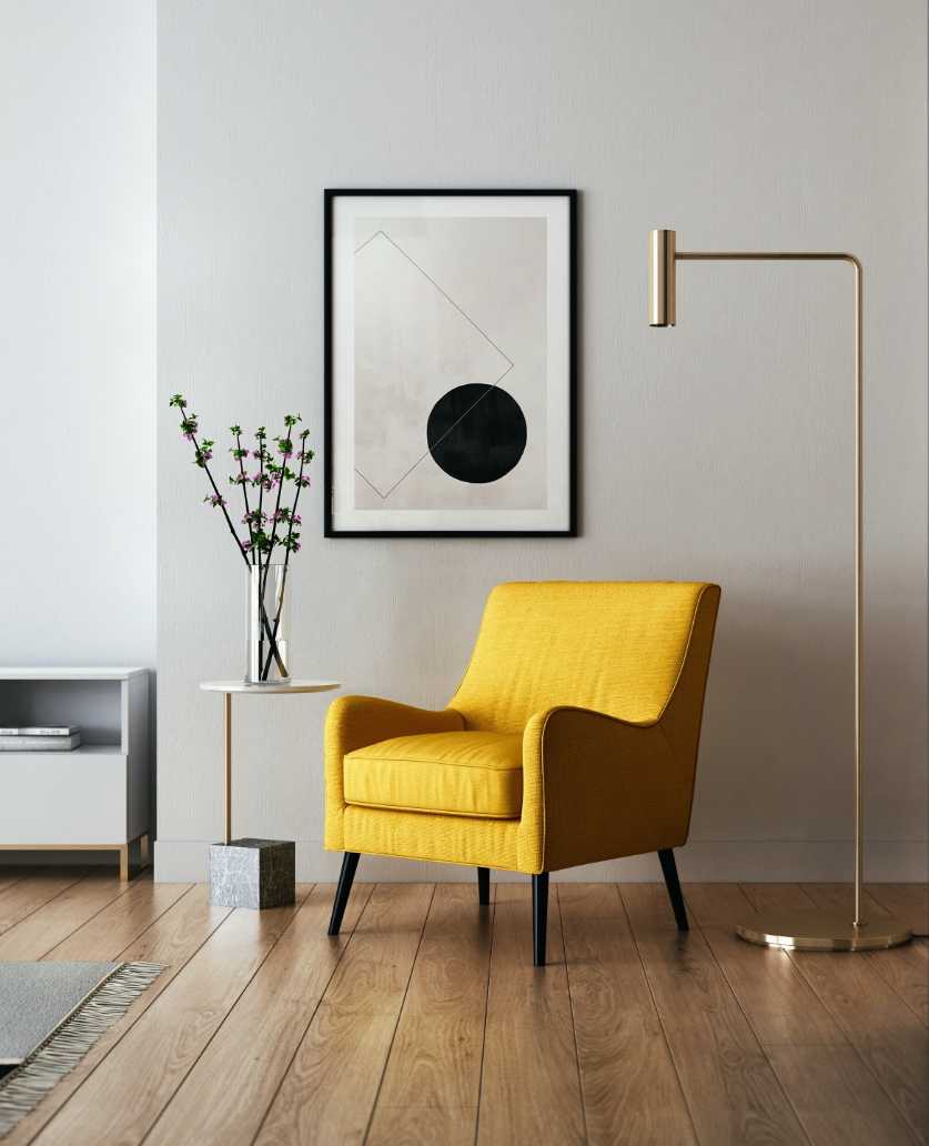 A yellow chair in front of a white wall.